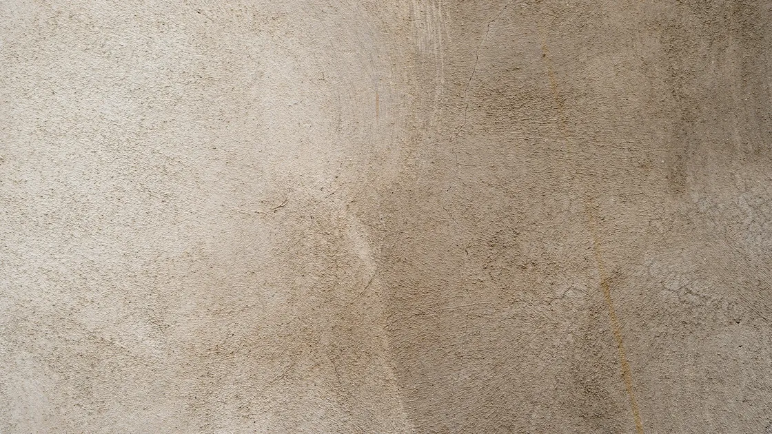 Paramento revestido con estuco de cal de tono cálido, con textura irregular y marcas suaves dejadas por la llana